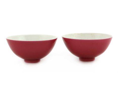 A pair of Chinese ruby-enamelled tea bowls,each steep rounded side rising from a circular foot, the exterior covered overall 
