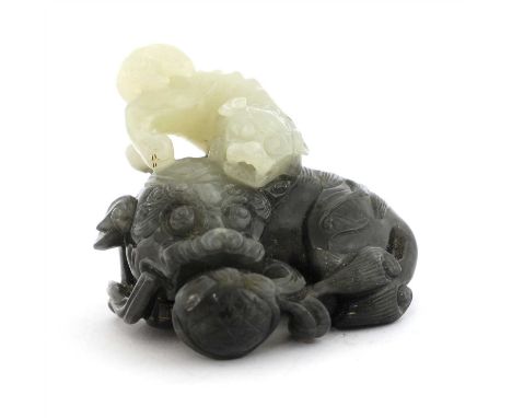 A Chinese jade carving, Qing dynasty (1644-1911), carved with a recumbent Buddhist lion holding a brocade ball in its mouth, 