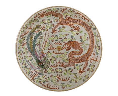 A large Chinese famille rose charger, the rounded sides rising from a circular foot, painted with a phoenix and dragon chasin