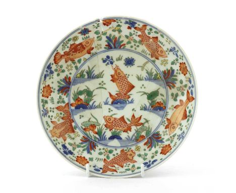 A Chinese wucai dish,Kangxi (1662-1722), the centre painted with two iron-red carp among weed in a lotus pond, the well and u