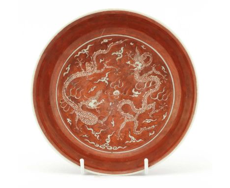 A Chinese iron red-glazed plate, the rounded sides rising from a circular foot, painted with two dragons chasing a flaming pe