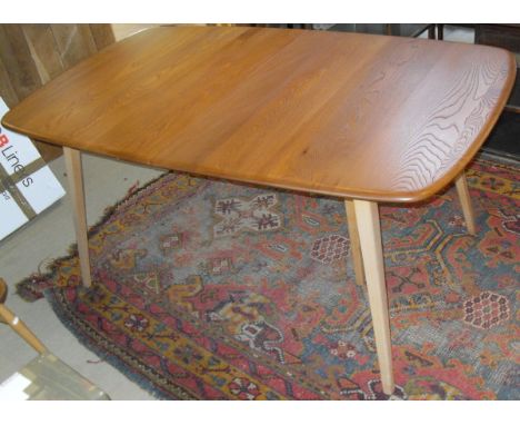 A light elm Ercol extending dining table on beech supports, together with four stick back elm seated Ercol chairs