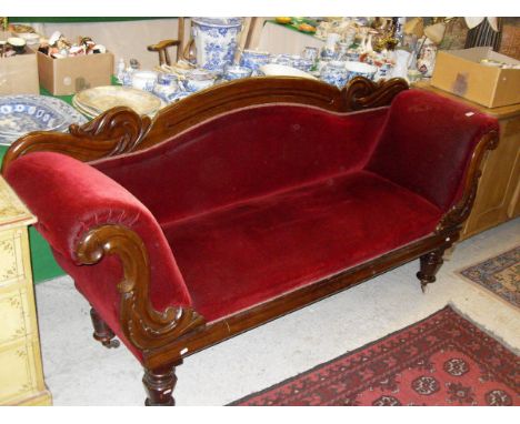 A Victorian mahogany framed scroll arm sofa with red velvet upholstery, raised on turned and carved legs to white china front