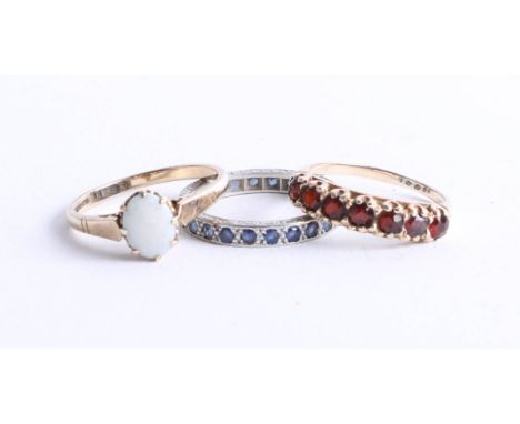 Three dress rings including, 9ct gold garnet ring, 9ct opal ring and a white metal sapphire full eternity ring (3).