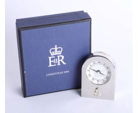 A small clock, silver effect presented by Queen Elizabeth II to the royal household Christmas 2005, boxed.