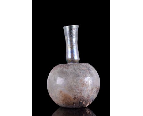 Ca. 1-400 AD.A clear glass flask featuring a spherical body with a concave base, and a constricted funnel-shaped neck with a 