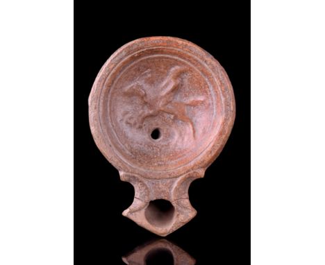Ca. 100 AD.A beautiful terracotta oil lamp with a circular concave discus with a small wick hole and decorated with a left-fa
