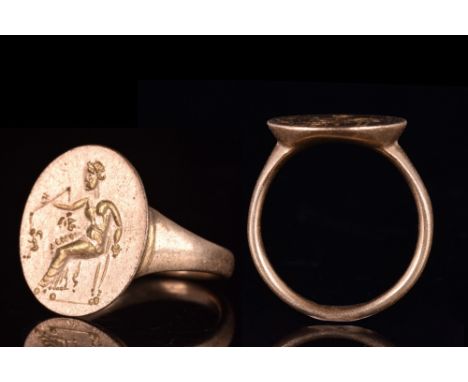 Ca. 100-300 AD.A beautiful gold ring with a round hoop and a large bezel setting featuring an engraved figure of seated Themi