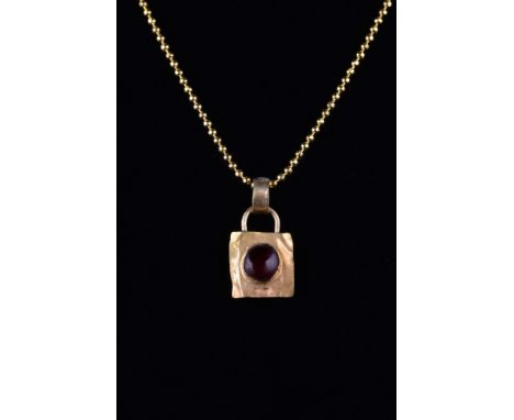 Ca. 100-300 AD.A gold pendant formed of a thin sheet of gold, modelled in the shape of a square. The centre is set with a bea