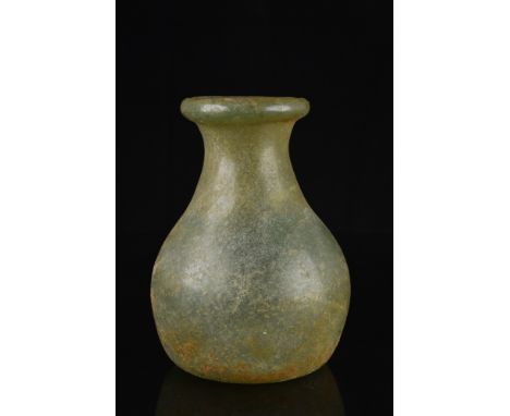 Ca. 100-300 AD.An olive-green free-blown glass flask featuring a spherical body on a concave base with a pontil scar, a short