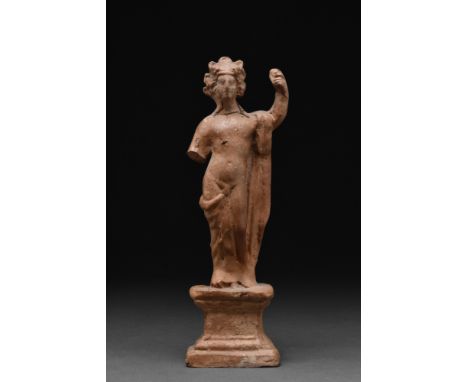 Ca. 1-100 AD.A terracotta statuette of a standing Bacchus (Greek Dionysus). He is depicted naked, standing atop an architectu