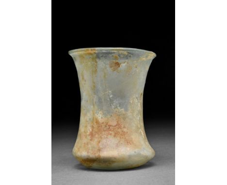 Ca. 200-300 AD.A yellowish-light green glass beaker with a flaring rim, lightly piriform body, and ring foot; slight encrusta