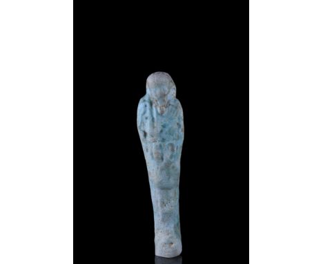 Late Dynastic Period, Ca. 664-332 BC.A light blue faience ushabti figure wearing a tripartite wig, a false beard, and holding