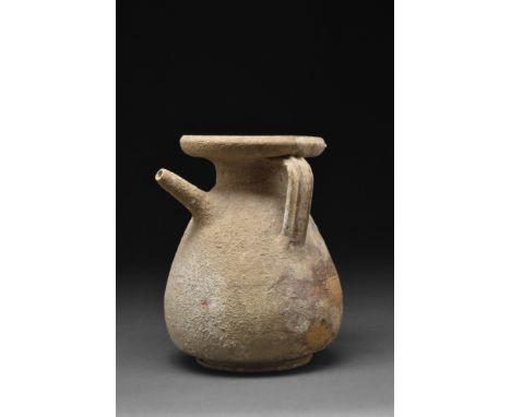 Ca. 300-200 BC.A bright brown pottery strainer jug with a piriform body on a ring base with a short neck, everted rim, and a 