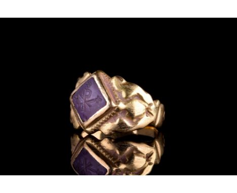 Ca. 600 AD.A gold finger ring of a flat-section hoop with wide, supportive shoulders. The bezel is set with an amethyst intag