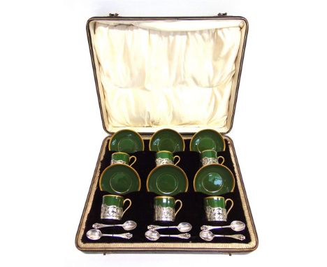 A CASED SET OF SIX CERAMIC COFFEE CANS AND SAUCERS with silver mounts and spoons, by George Wish Ltd, Sheffield 1907-08, the 