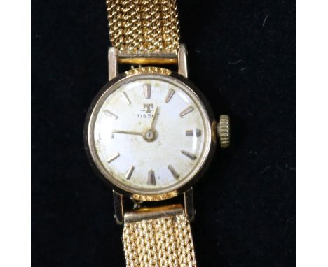 A lady's gold plated and steel Tissot manual wind wrist watch on a textured gold bracelet.