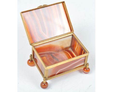 A 19th Century carnelian stone banded agate and gilt brass ormolu trinket box raised on four bun feet with hinged lid and pan