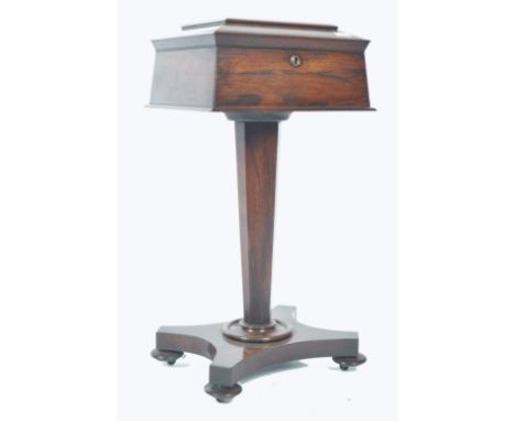 A 19th century Regency rosewood teapoy. Raised on a quadruped base with bun feet having hexagonal rising column supporting a 