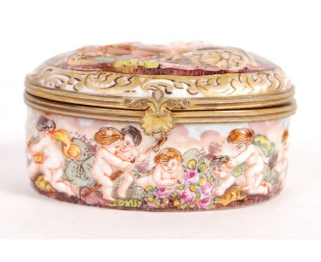 A 19th century Napals Capidimonte porcelain trinket box being relief decorated with cherubs with to the outside and the hinge