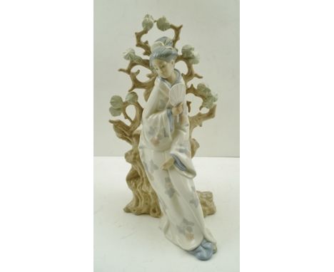 A LLADRO PORCELAIN FIGURINE OF A BIJIN, seated upon a pine trunk, 31cm high 