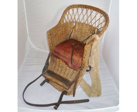 A CHILD'S WOVEN WICKER BASKET SEAT with red leather pad (a collectable item, for restoration) bearing retail label "Harrod's 