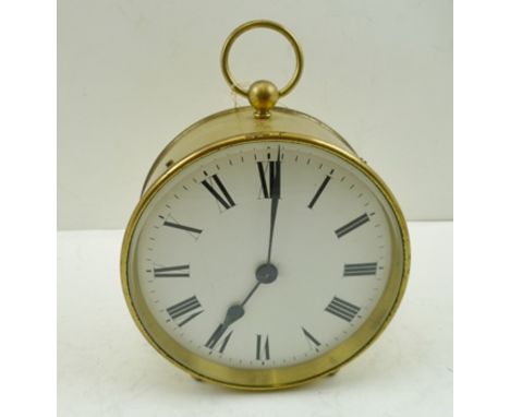 AN EARLY 20TH CENTURY BRASS CASED TIMEPIECE with carrying ring to top, angled with two button feet at front of base, white en