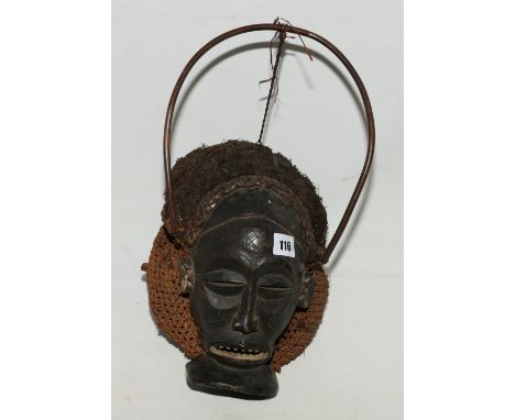 African mask with scarified face and wide toothed mouth, full woven fibre head cover and fibre hair with bent cane tensioned 