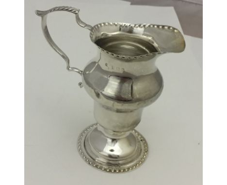 A hallmarked silver creamer with hammered button rims