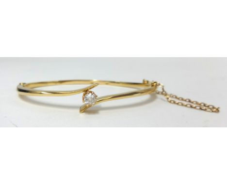 An 18ct yellow gold bangle set with a single round cut diamond, approx 7.60gms.