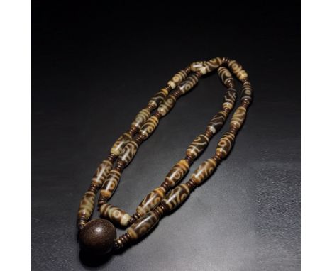 Tooth-yellow fine patinated old agate two-eyed dzi bead rosary necklace is held in hand. It is oily, delicate and full of wea
