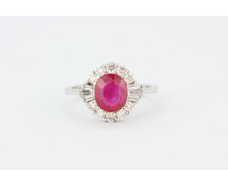 An 18ct white gold cluster ring set with a large oval cut ruby, approx. 2.15ct, surrounded by brilliant and baguette cut diam