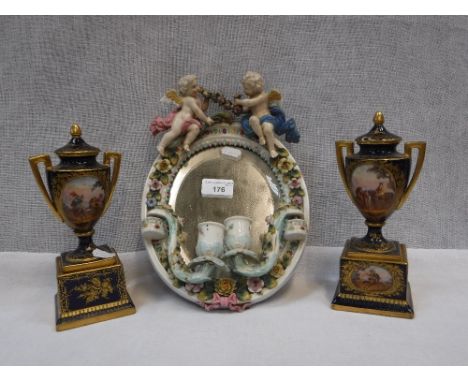 A LATE 19TH CENTURY CONTINENTAL PORCELAIN FRAMED OVAL WALL MIRROR, decorated with cherubs fitted candle sconces, 11" high and