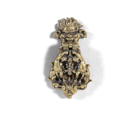 A CAST BRASS RENAISSANCE STYLE DOOR KNOCKER, 19TH CENTURY, in the form of a human mask holding a cartouche supported by putti