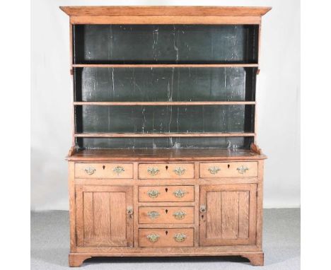 An 18th century Welsh oak dresser, having a boarded back, over an arrangement of short drawers and cupboards, on bracket feet