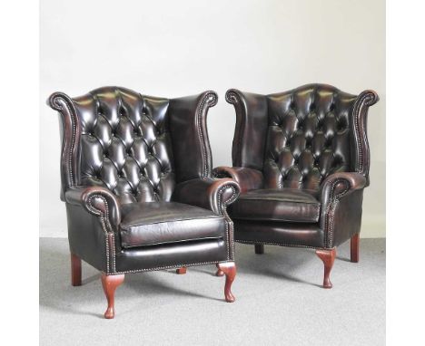 A pair of brown leather upholstered button back wing armchairs, on cabriole legs (2)