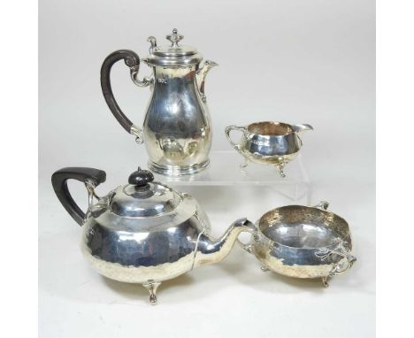 An Edwardian Art Nouveau silver three piece tea service, comprising teapot, 24cm long, sugar bowl and cream jug, with planish