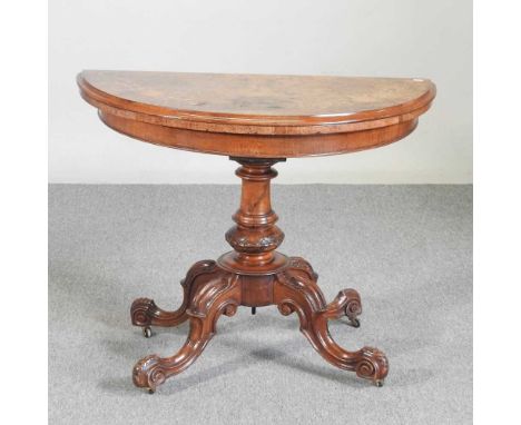 A Victorian burr walnut and marquetry folding card table, with a hinged half round top, on a carved column and quadruped pede