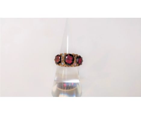 A 9 carat gold three stone garnet ring, the oval cuts with small opal points between, finger size N, 4.2 g gross