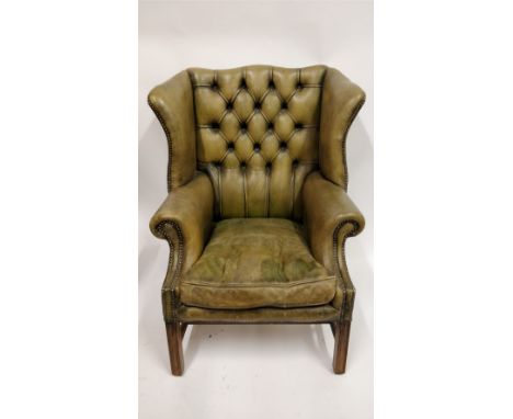 A 20th century green leather button back wingback armchair