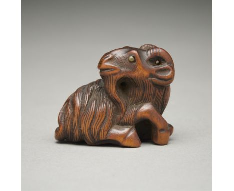 19th c. Japanese carved wooden netsuke in the form of a goat with inlaid black eyes. He raises his head while looking back an