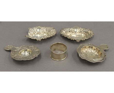 A pair of silver pierced dishes, a napkin ring and two strainers. The former 10 cm wide. 3.5 troy ounces.