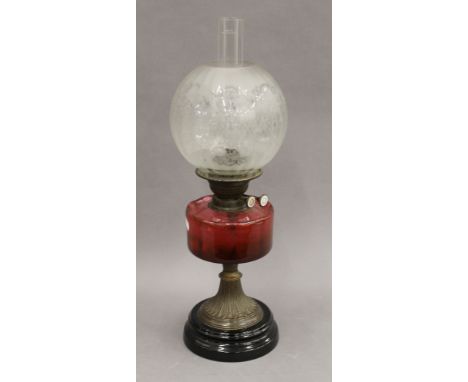 A Victorian oil lamp with cranberry glass reservoir. 56 cm high overall.