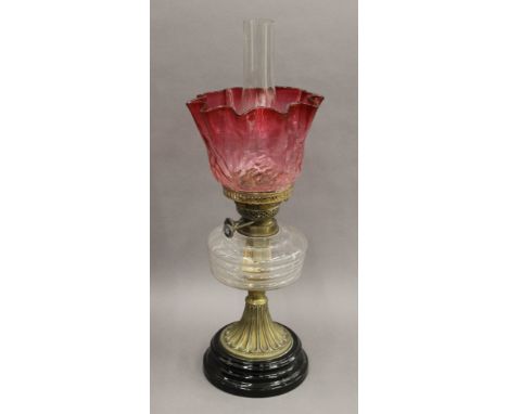 A Victorian oil lamp with cranberry glass shade. 56 cm high overall.