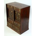 A SMALL JAPANESE HARDWOOD CABINET, onlaid with various metal menuki, comprising two sliding doors,