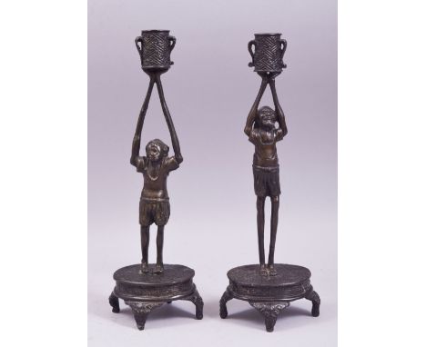A PAIR OF JAPANESE BRONZE FIGURAL CANDLESTICKS, each formed as a male figure upon a base with arms raised supporting the cand