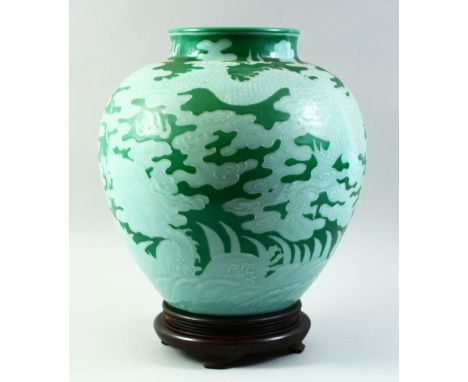 A VERY LARGE UNUSUAL CHINESE GREEN GROUND DRAGON VASE and hardwood stand, decorated with a dragon amongst stylised clouds, fl