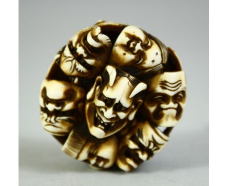 A JAPANESE CARVED IVORY NETSUKE, carved as a roundel of noh masks, signed, 4.5cm.