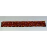 A TURKAMAN BELT, black ground, embroidered in red and yellow thread to geometric design, 75cm x