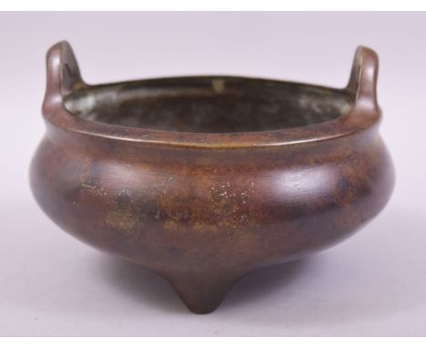 A CHINESE BRONZE TWIN HANDLE TRIPOD CENSER, with four character mark to base, 15cm diameter.